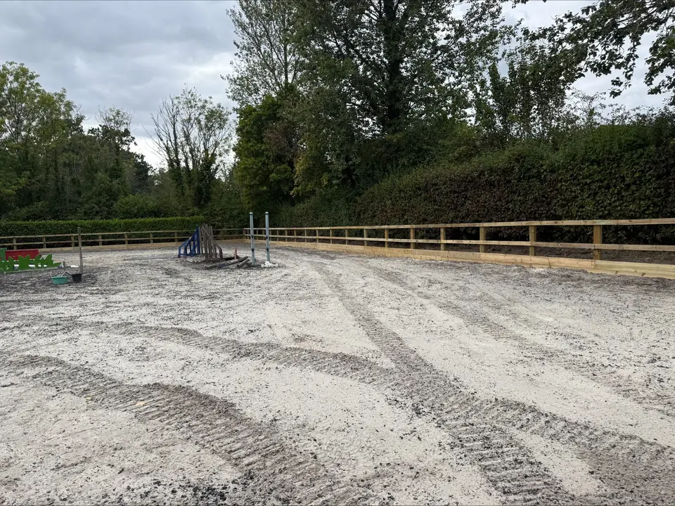 Horse riding arena with timber post and rail fencing and show jumps