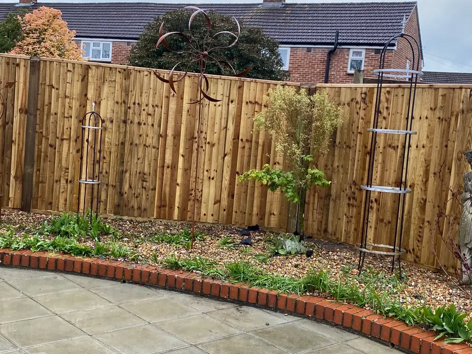 Close-up of timber garden fencing behind flower beds