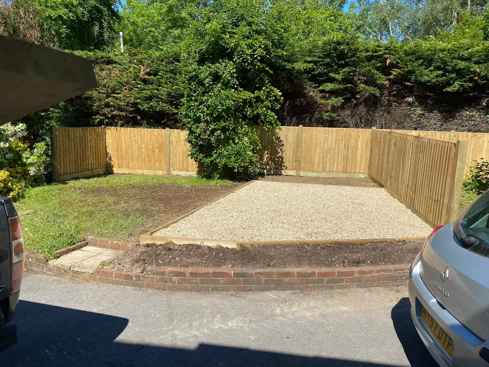 Timber fencing enclosing a gravel area beside woodland