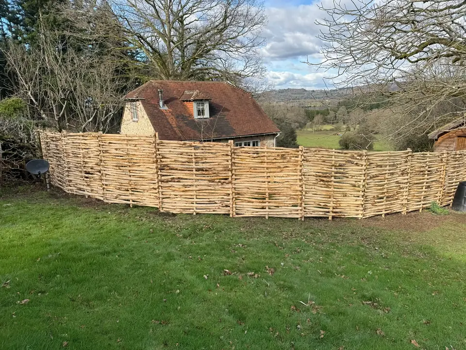 Woven rustic timber fencing across a sloping garden